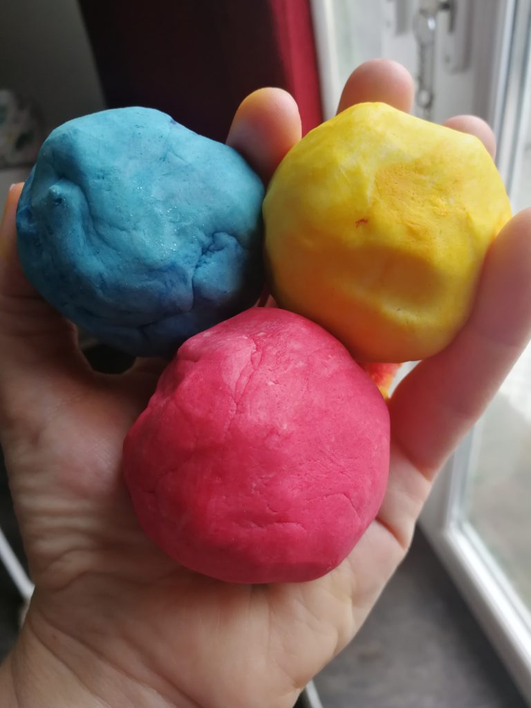 Image of someone holding playdoh balls in the primary colours