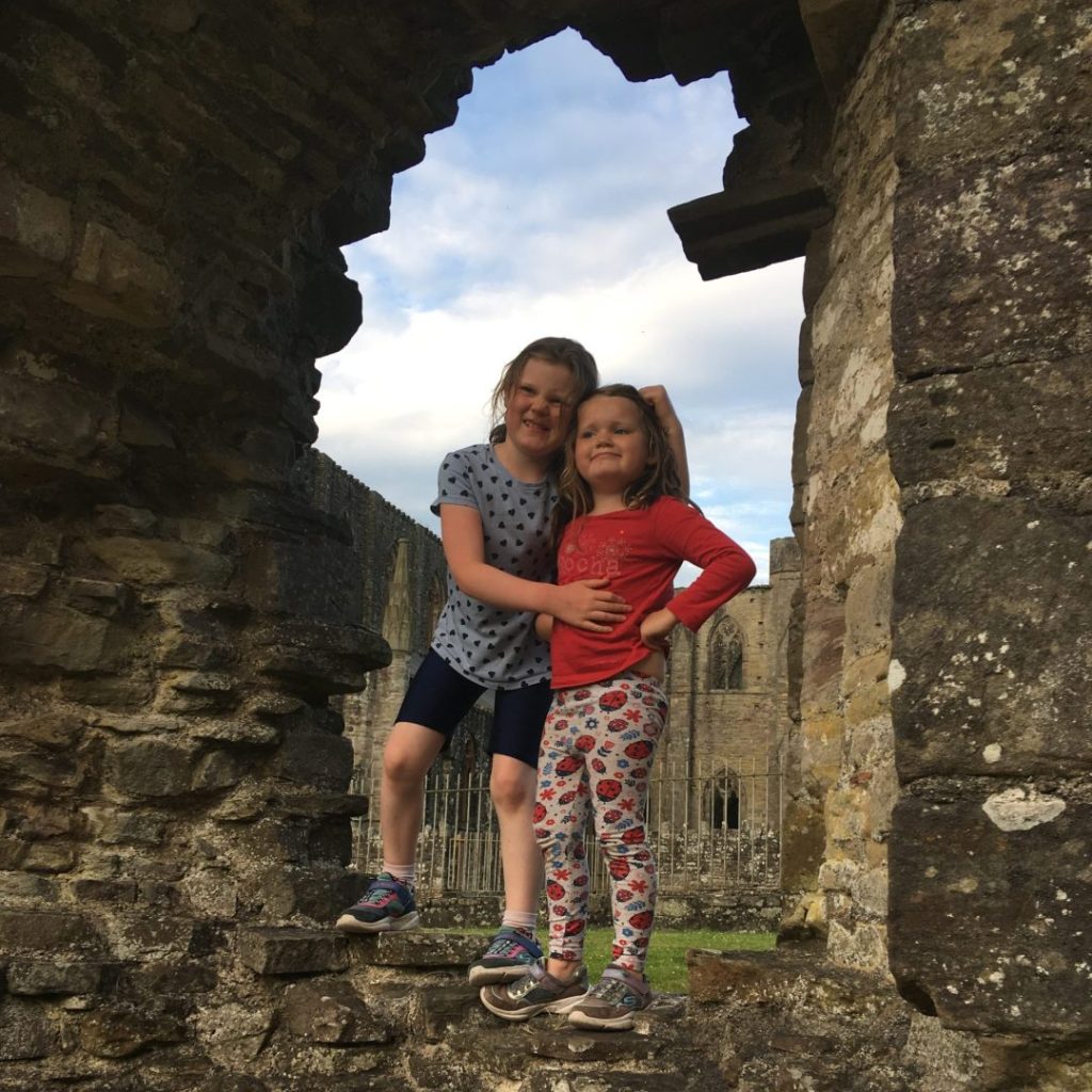 Two young Home Educated girls standing on the ruins of a castle