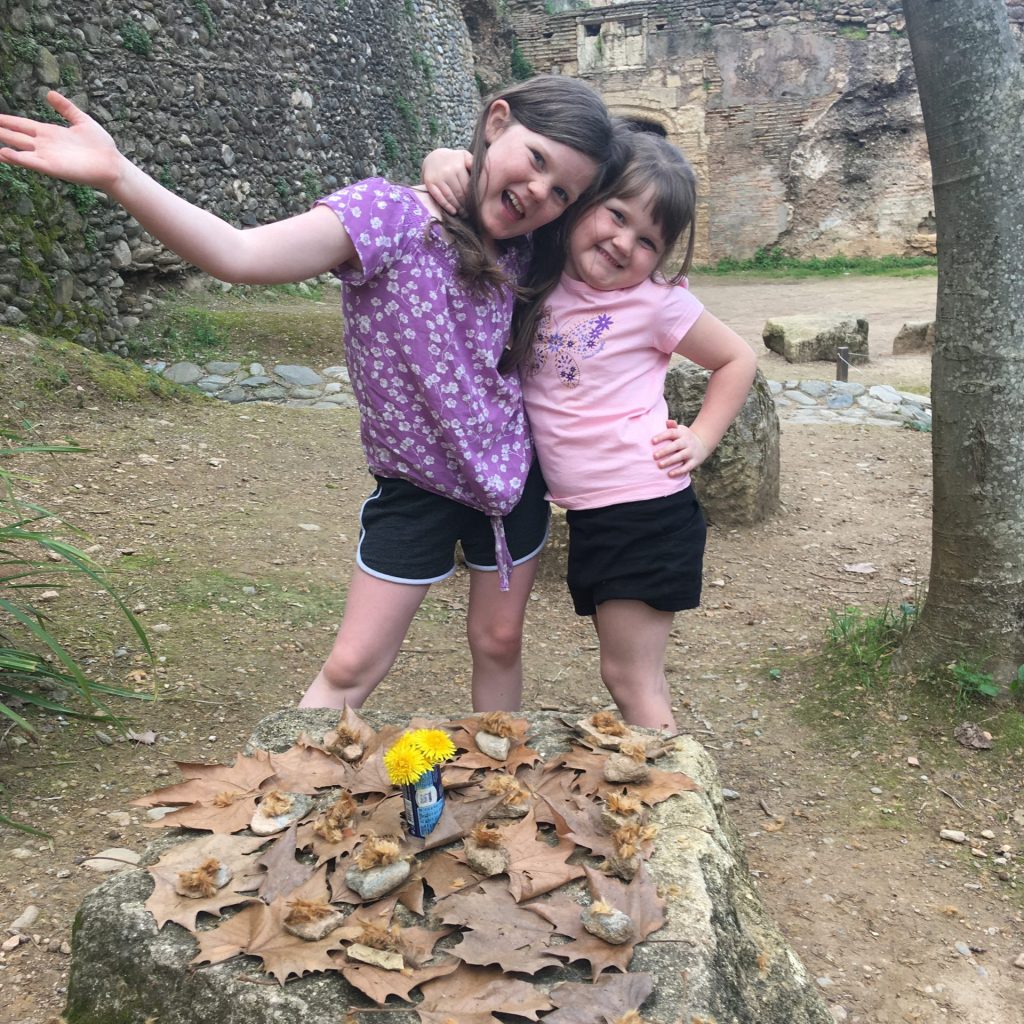 Two girls playing tea party outside with nature items