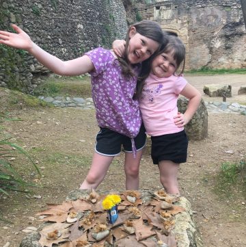 Two girls playing tea party outside with nature items