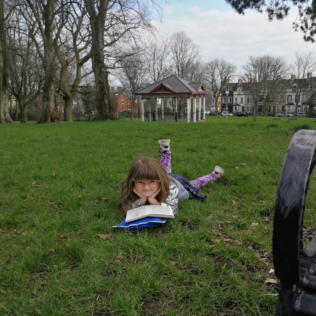 Young girl in glasses reading in the park